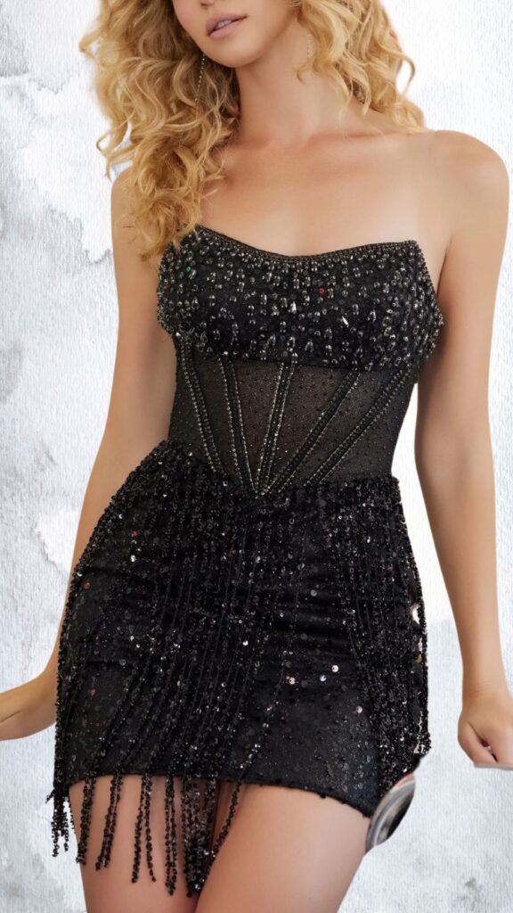 The dress features a fitted silhouette with a strapless neckline, showcasing an embellished bodice adorned with shimmering black beads and intricate rhinestone detailing. It has a flared skirt with a playful hemline, enhanced by cascading sequins and mesh panels, creating a dynamic texture that brings sparkle to movement. The combination of cutouts and fringe elements adds a contemporary edge while highlighting the wearer's figure.