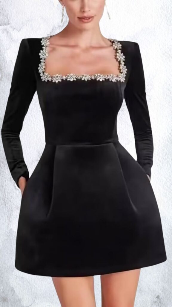 A fitted black mini dress features a structured silhouette with long sleeves and a square neckline embellished with floral rhinestone detailing. The dress flares gently at the waist and ends above mid-thigh, highlighting a clean hemline with side pockets for added functionality. The soft fabric enhances the elegant look, making it suitable for both casual and formal occasions.
