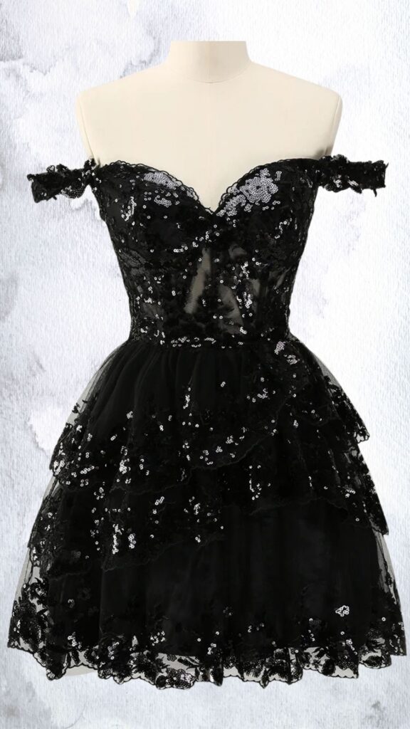 This black mini dress features an off-the-shoulder silhouette with a sweetheart neckline, showcasing intricate embellishments of sequins and beads that create a shimmering effect. The fitted bodice flows into a layered, ruffled skirt that adds volume, finishing at mid-thigh length with a scalloped hemline. The overall design combines elegance and playfulness, making it suitable for special occasions.