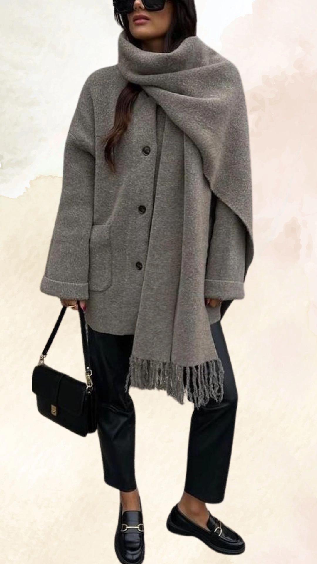 The outfit features a loose-fitting, light gray wool coat with a collar and large buttons, paired with a matching oversized scarf draped around the neck. The ensemble is completed with black high-waisted faux leather trousers and stylish black loafers adorned with a decorative buckle. The overall look is both chic and cozy, perfect for casual fall outings.