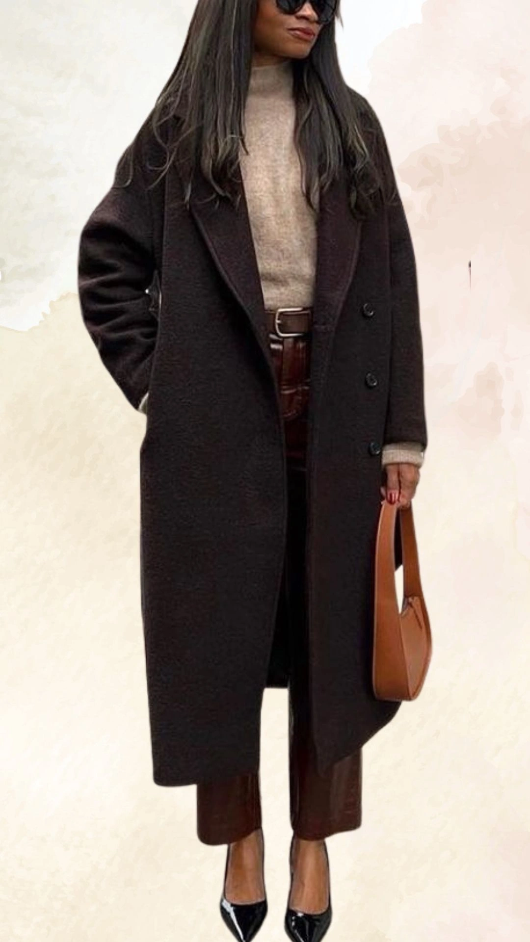 The outfit features a long, dark brown, oversized coat with a notch lapel and button closures, layered over a light taupe turtleneck sweater. Paired with fitted brown pants that have a slight gloss sheen, the look is complemented by black pointed-toe heels and a structured brown handbag, creating a chic and polished fall ensemble.