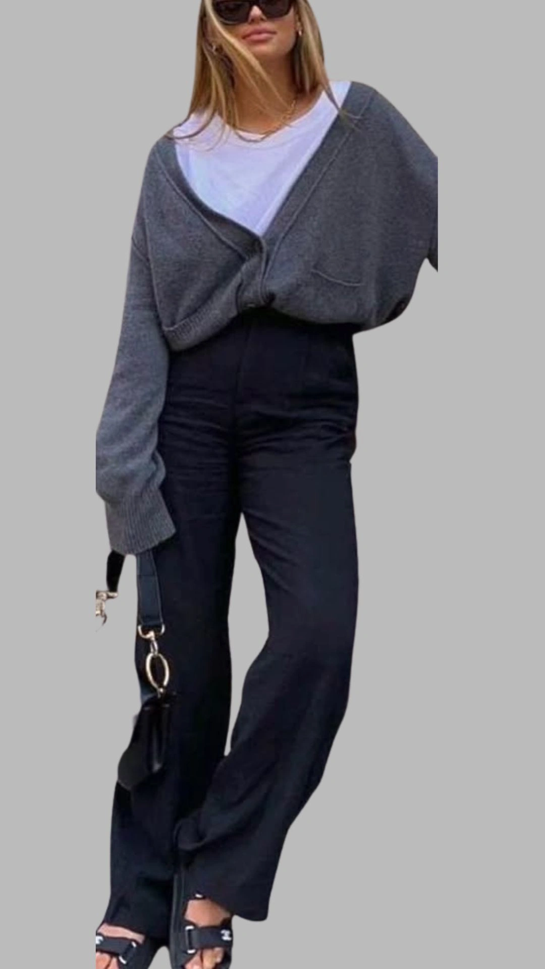 The outfit features a cozy, oversized grey cardigan with a deep V-neckline and long, wide sleeves, layered over a simple white t-shirt. Paired with high-waisted, black wide-leg trousers, the ensemble balances comfort and style, while the look is completed with black platform sandals. This combination showcases a modern and chic approach to grey outfit ideas, emphasizing relaxed elegance.