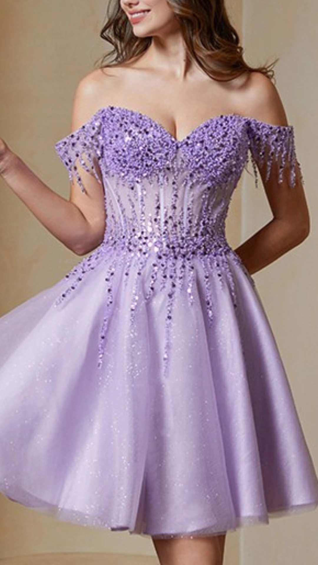The dress is a playful A-line design in a soft lavender shade accented with shimmering sequins and delicate, beaded fringes around the off-shoulder neckline, creating an elegant yet youthful appearance. The fabric has a light, textured tulle overlay, giving the dress a magical, ethereal vibe, perfectly suited for a homecoming or school dance for teenage girls.