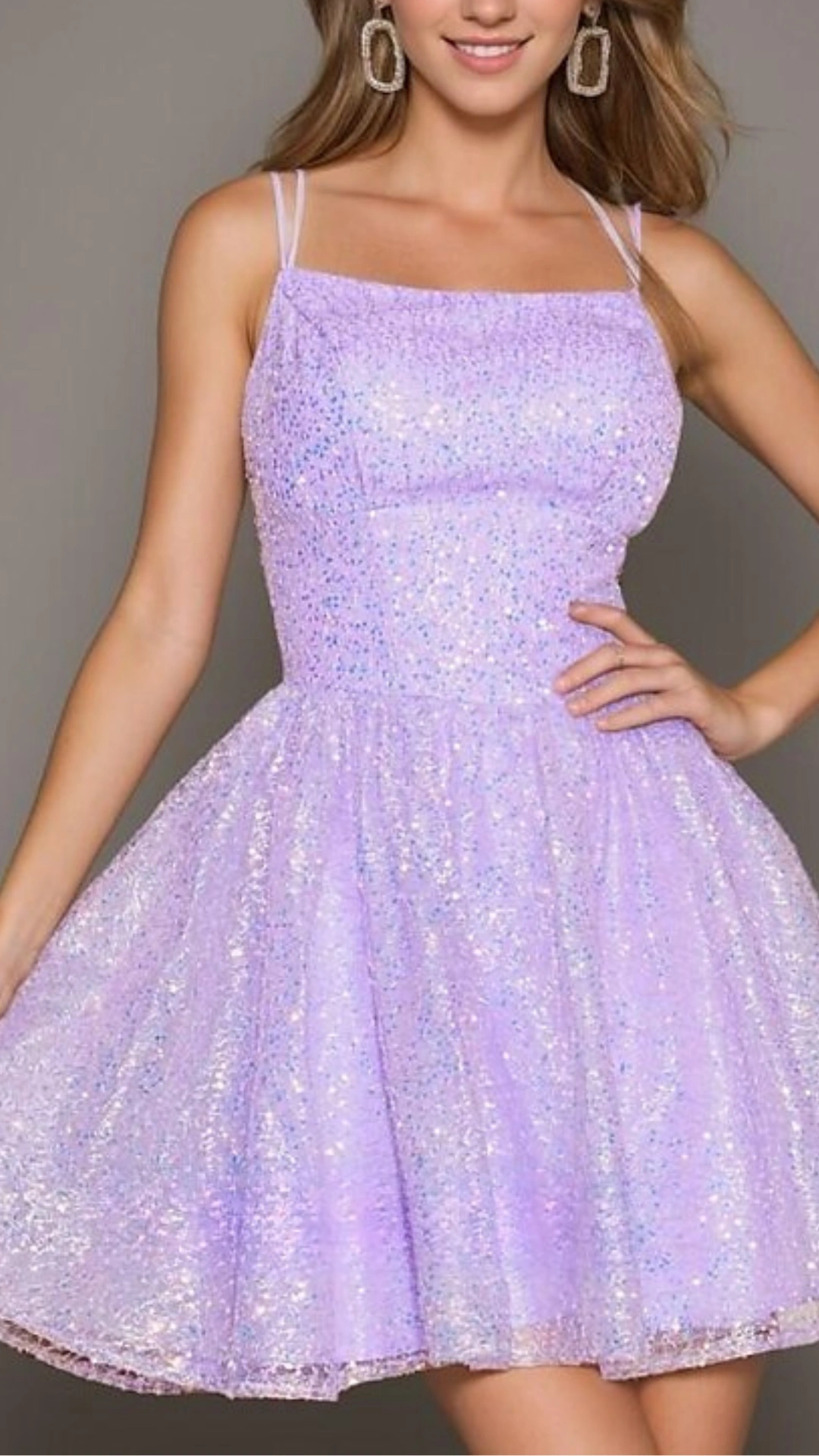 This charming homecoming dress is a light lavender hue adorned with shimmering sequins, creating a sparkly, ethereal effect. The fitted bodice leads into a flared skirt, offering a playful volume, perfect for a teenage girl looking to make a statement at a formal event or school dance.
