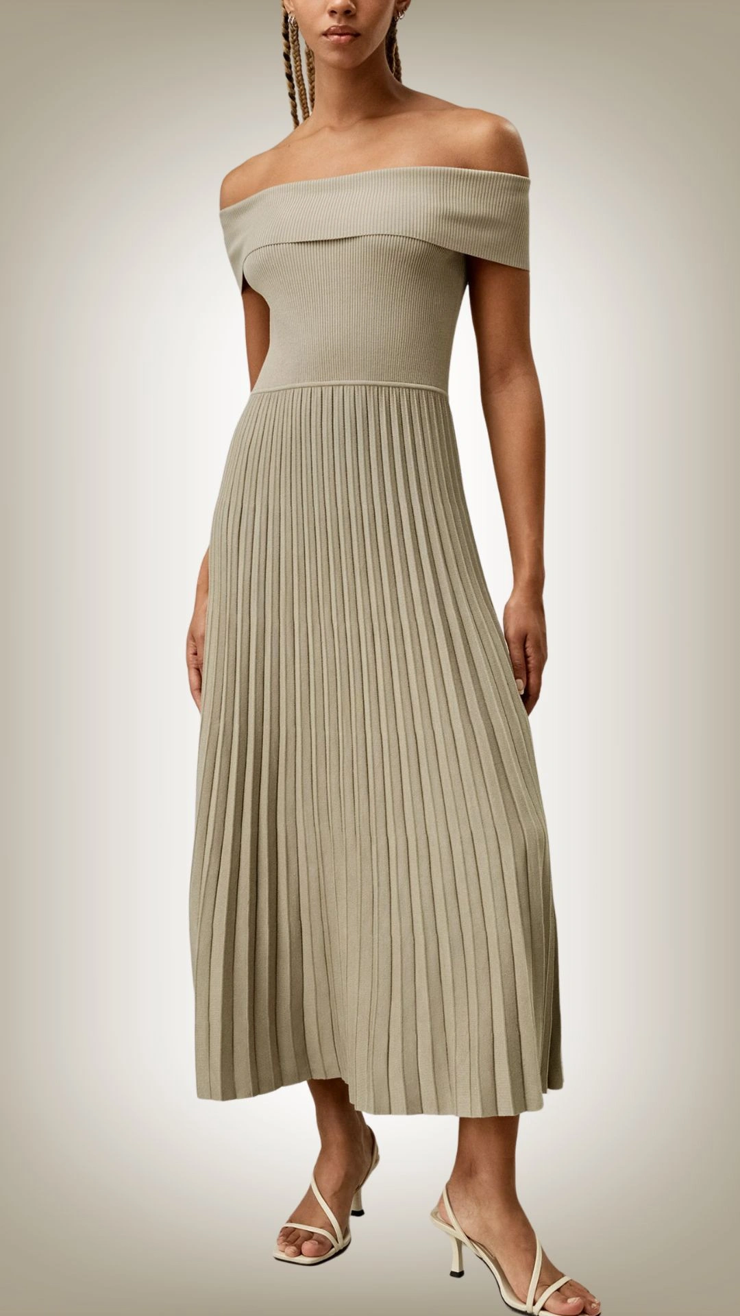 This off-the-shoulder sweater dress features a ribbed texture and a fitted bodice that seamlessly transitions into a flowing, pleated skirt, creating a refined silhouette. The dress is adorned in a soft, muted sage green, enhancing its elegant and contemporary feel. With a mid-length cut, it offers a balance of sophistication and comfort, making it suitable for various occasions.