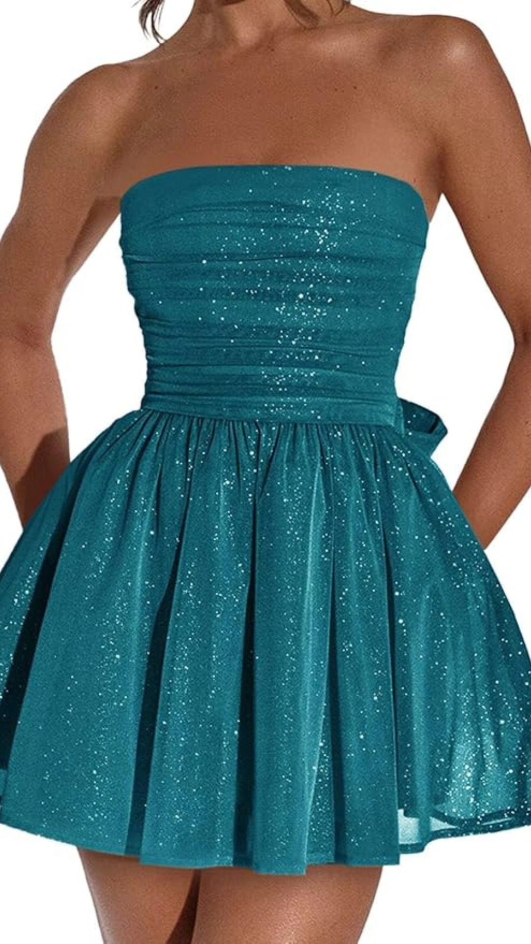 This strapless homecoming dress is crafted from a shimmering teal fabric that sparkles with a subtle glitter finish, enhancing its playful charm. The fitted bodice leads into a voluminous, flared skirt that creates a youthful and whimsical silhouette, perfect for a teenage girl's celebration at a formal event or dance.