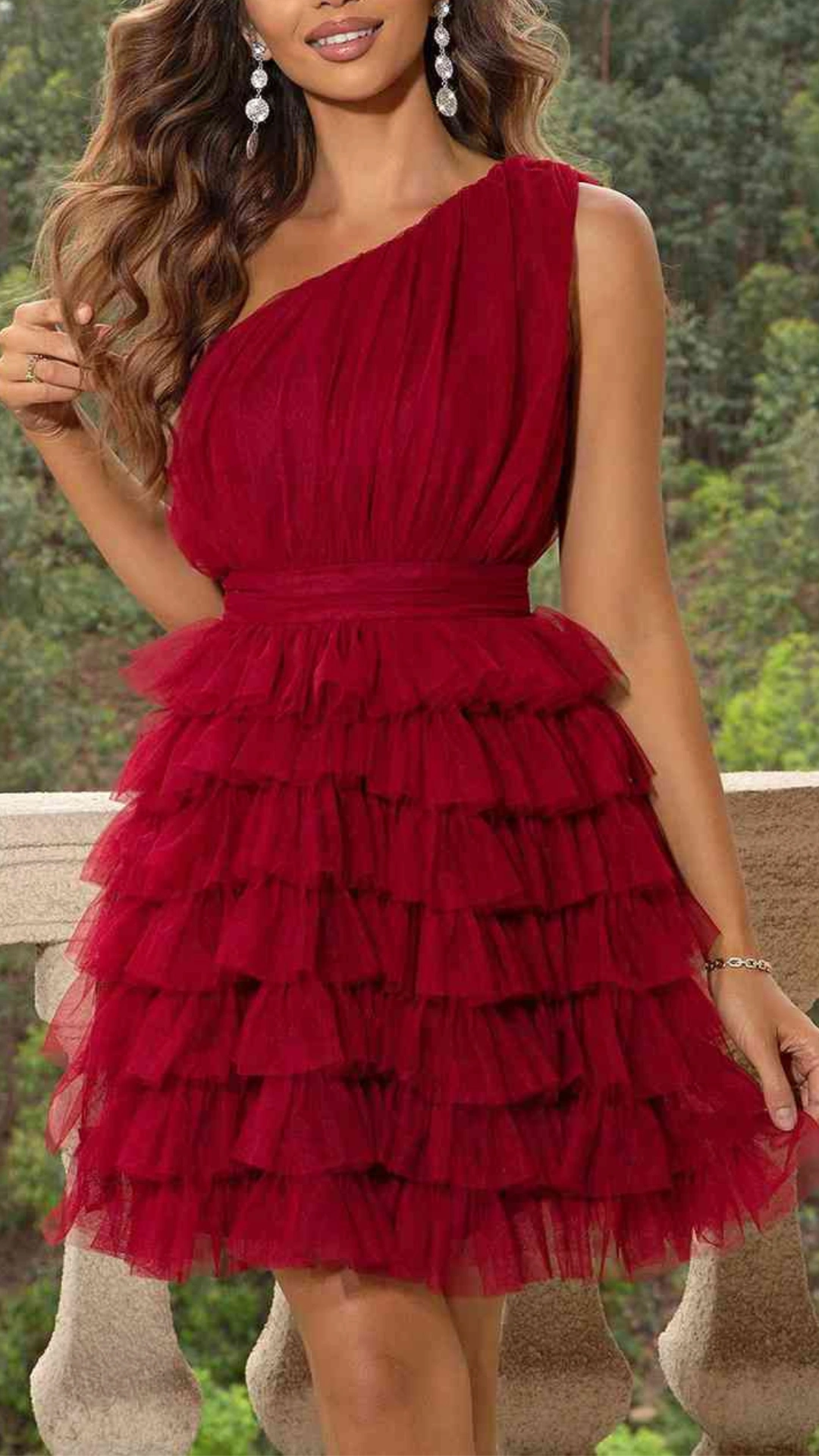 This vibrant red homecoming dress features a one-shoulder design with a fitted bodice and a playful, layered tulle skirt that adds volume and movement. The rich crimson hue and soft sheer texture create a romantic, whimsical vibe, perfect for teenage girls attending a formal event or school dance.