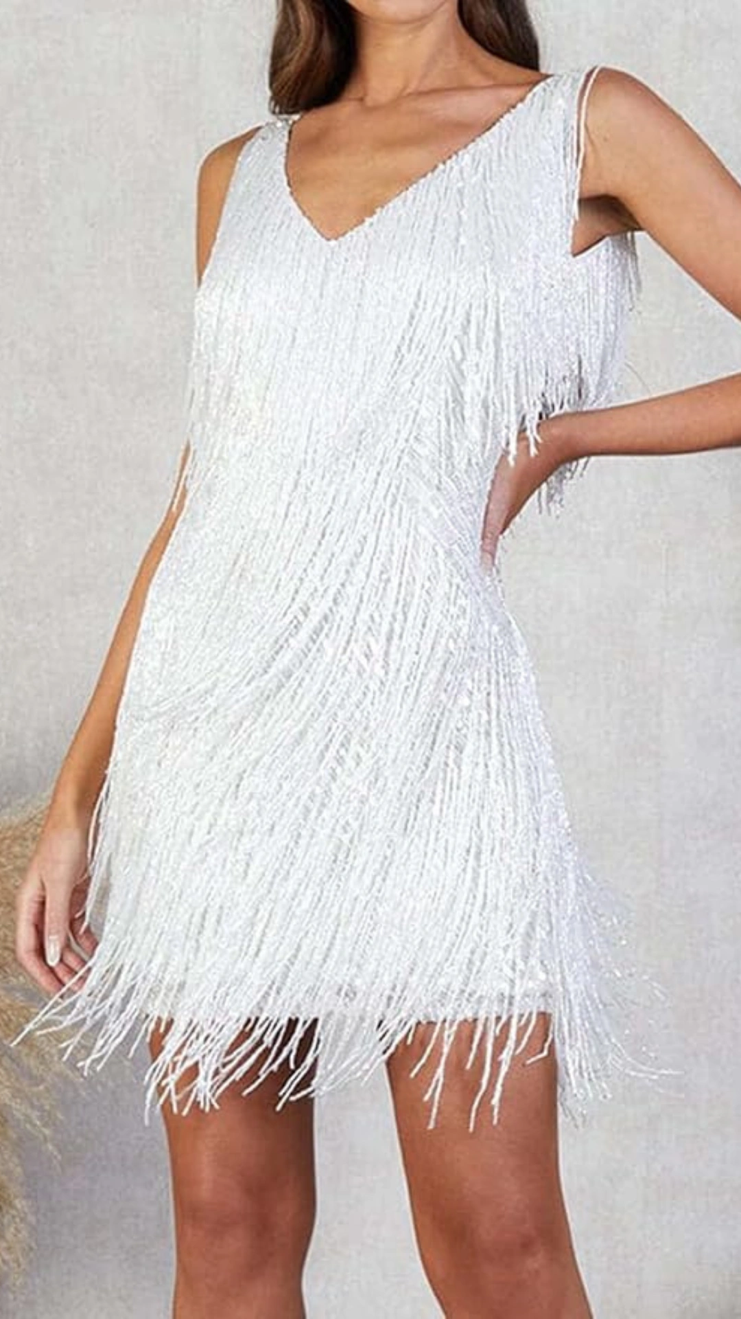 This white homecoming dress features a chic A-line silhouette with a V-neckline and a flapper-inspired design, adorned with shimmering fringe that adds a playful texture. Ideal for a lively party atmosphere, the dress offers a fitted style that flatters the figure, creating a fun and trendy vibe for teenage girls at special events.